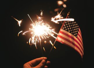 a hand holding an american flag and a sparkler