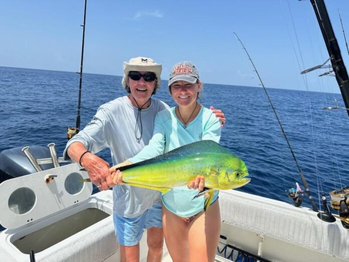 Attach0 a man and woman on a boat holding a fish