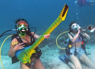 two women in scuba gear are playing instruments in the water