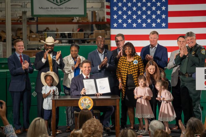 DeSantis signs immigration bill Large a group of people standing next to each other on a stage