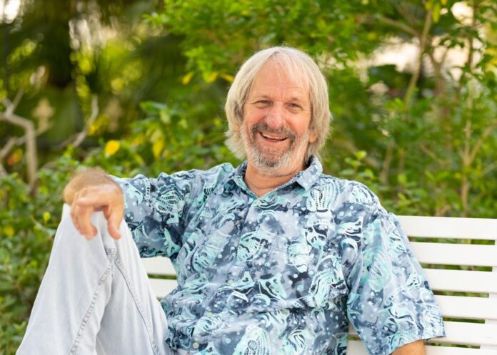 a man sitting on a white bench holding a shirt
