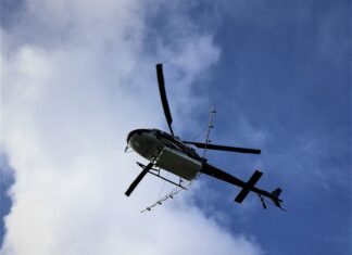 a helicopter flying through a cloudy blue sky