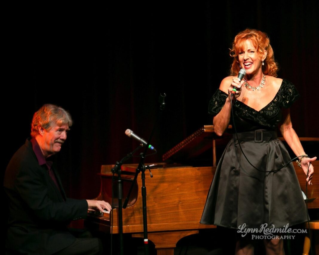 a woman in a black dress singing into a microphone