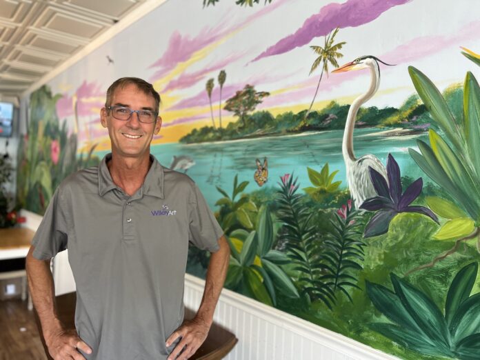 a man standing in front of a mural