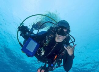 a man in a scuba suit holding a camera in the water