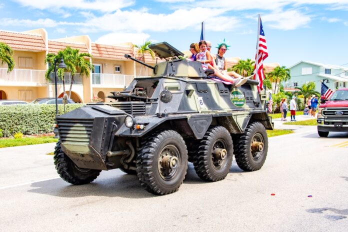 a military vehicle driving down a street next to palm trees