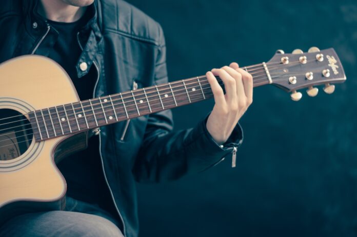 a man holding a guitar while sitting down