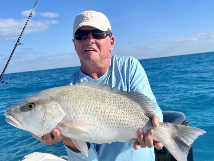 a man on a boat holding a fish