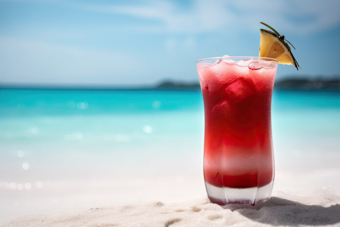 a red drink sitting on top of a sandy beach