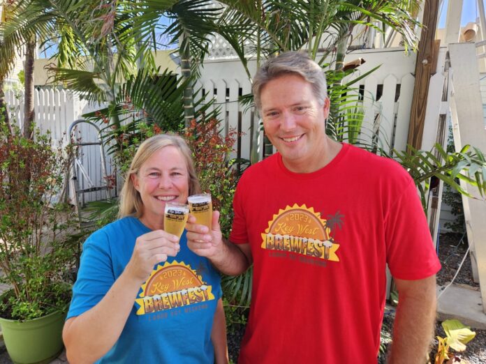 a man and a woman standing next to each other holding glasses of beer