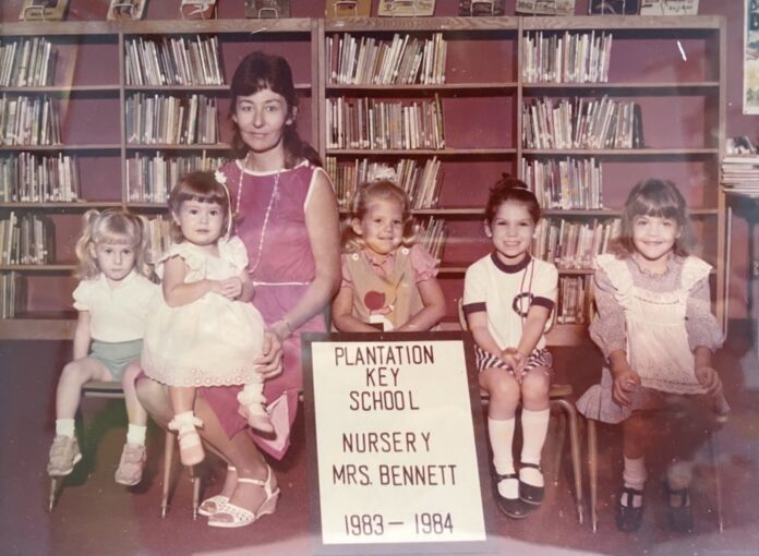 a group of children sitting in front of a sign