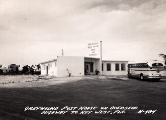 a black and white photo of a bus parked in front of a building