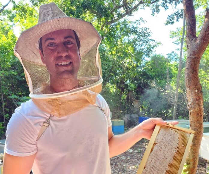 a man in a hat holding a beehive