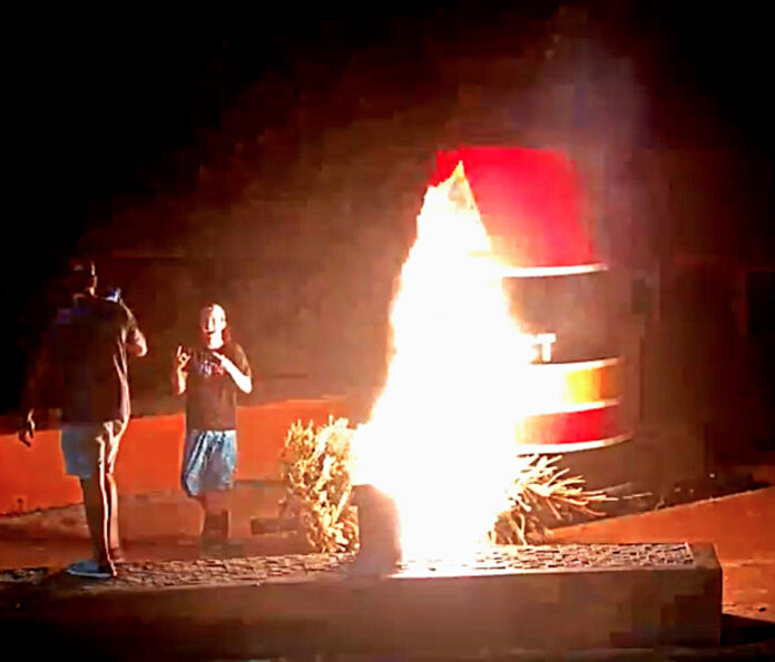 a couple of people standing next to a fire