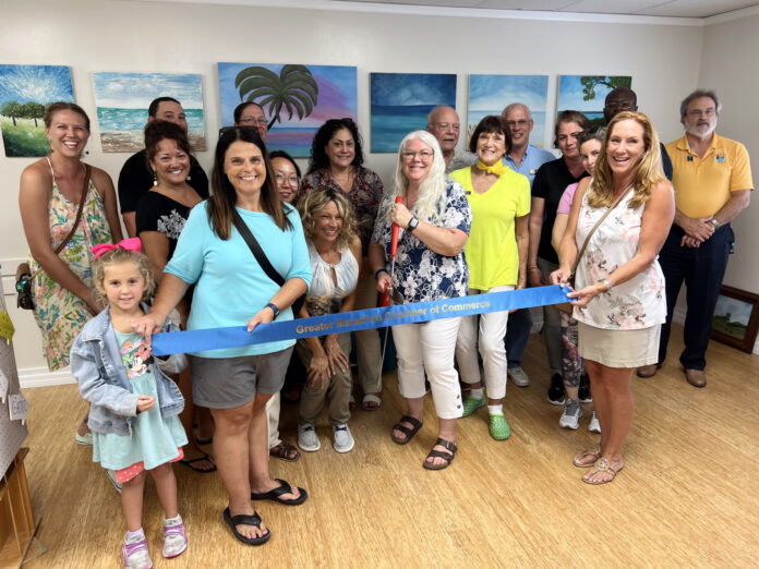 a group of people standing in a room holding a blue ribbon