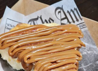 a hot dog with caramel drizzled on top of it