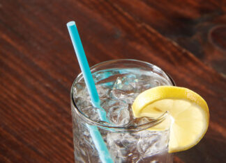a glass with a blue straw and a lemon on a wooden table