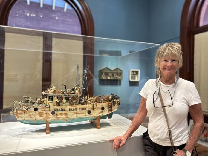 a woman standing next to a model of a boat