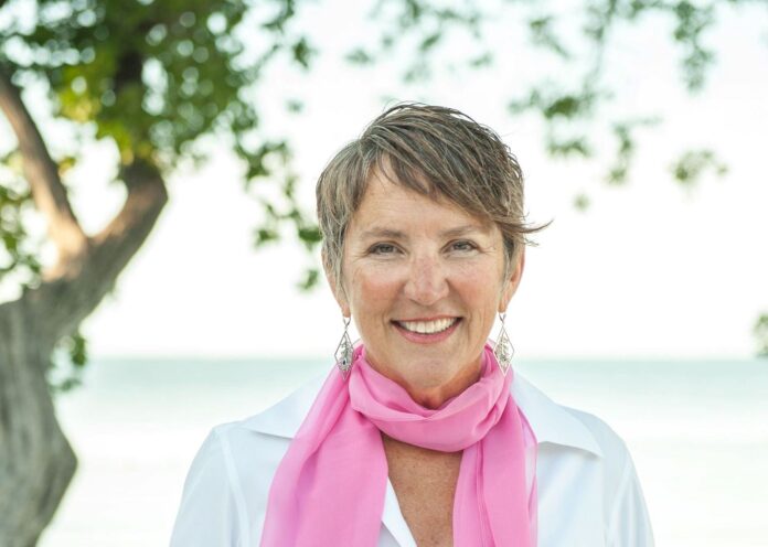 a woman wearing a pink scarf standing in front of a tree