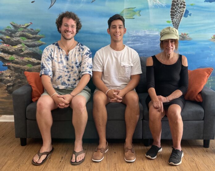 three people sitting on a couch in front of a mural