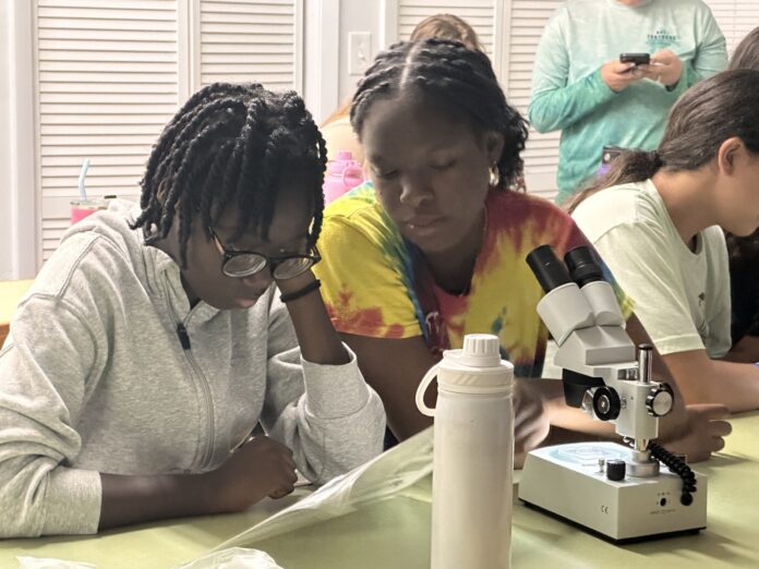 a group of people sitting at a table with microscopes
