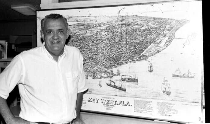 a black and white photo of a man standing in front of a map