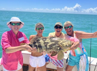 a group of people on a boat holding a fish