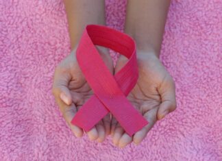 a person holding a pink ribbon in their hands