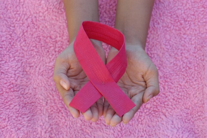 a person holding a pink ribbon in their hands
