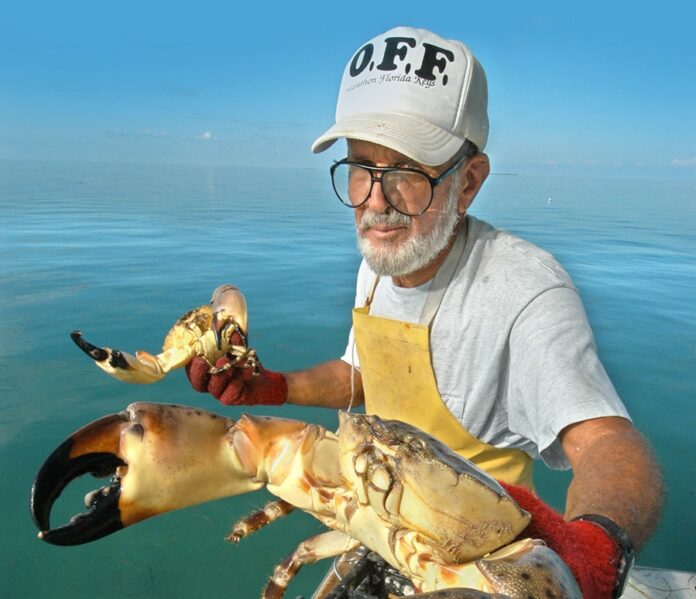 a man holding a large crab in the water