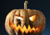 a carved pumpkin with glowing eyes and a spider
