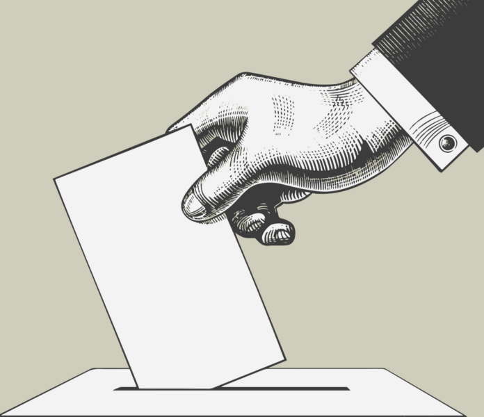 a hand putting a voting paper into a voting box