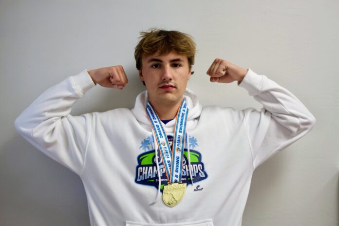 a young man wearing a white hoodie with a gold medal around his neck
