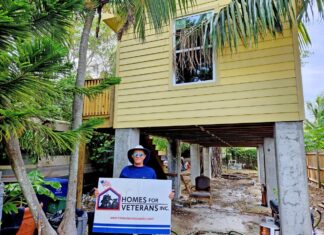 a man holding a sign in front of a house