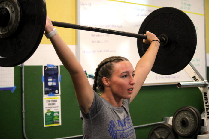 a woman lifting a barbell in a gym