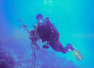 a man in a scuba suit is holding a pole in the water