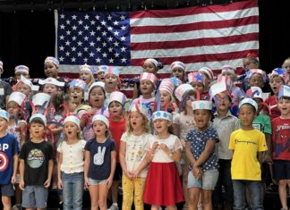 a group of children standing in front of an american flag