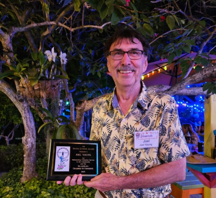 a man holding a plaque in front of a tree