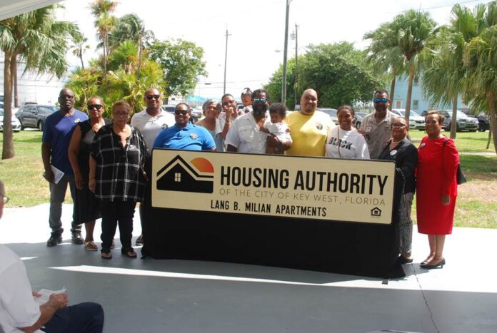 a group of people standing in front of a housing authority sign