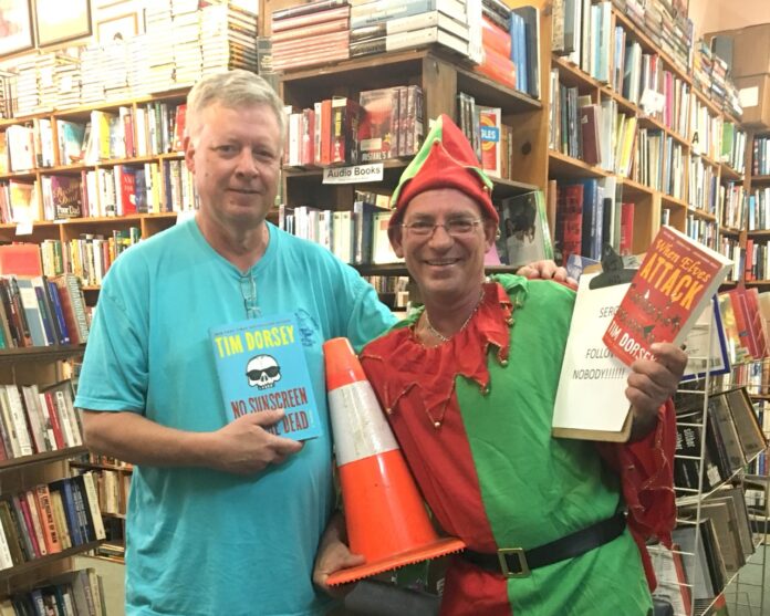 a couple of men standing next to each other in front of a book shelf