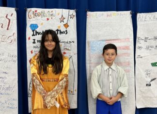 a boy and a girl standing in front of a blue curtain