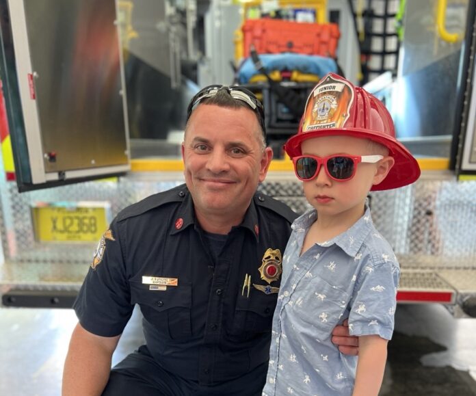 a man and a young boy in front of a fire truck