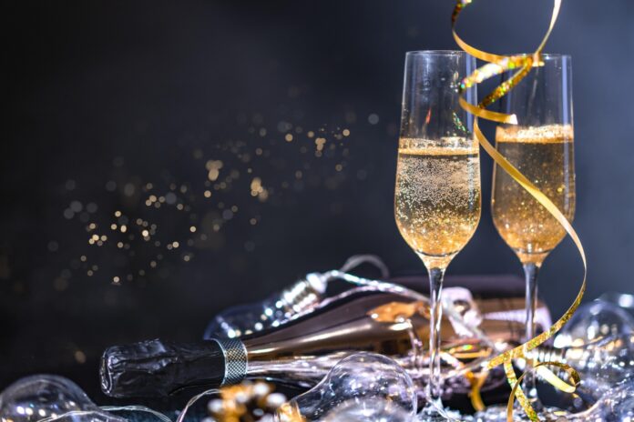 two glasses of champagne with a bottle of champagne in the background