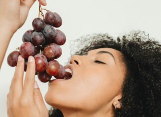 a woman holding a bunch of grapes up to her face