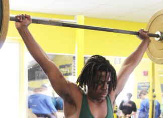 a man with dreadlocks lifting a barbell