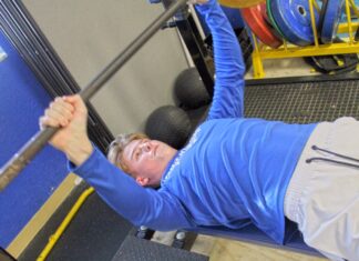 a man in a gym lifting a bar