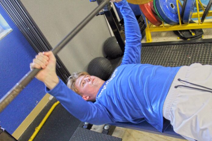 a man in a gym lifting a bar
