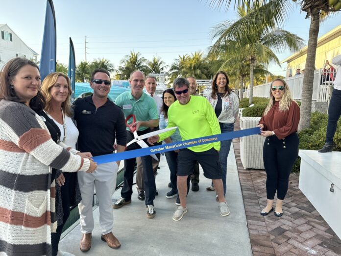 a group of people standing around a ribbon cutting