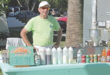 a man standing next to a blue table covered in drinks