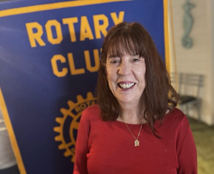 a woman standing in front of a rotary club sign